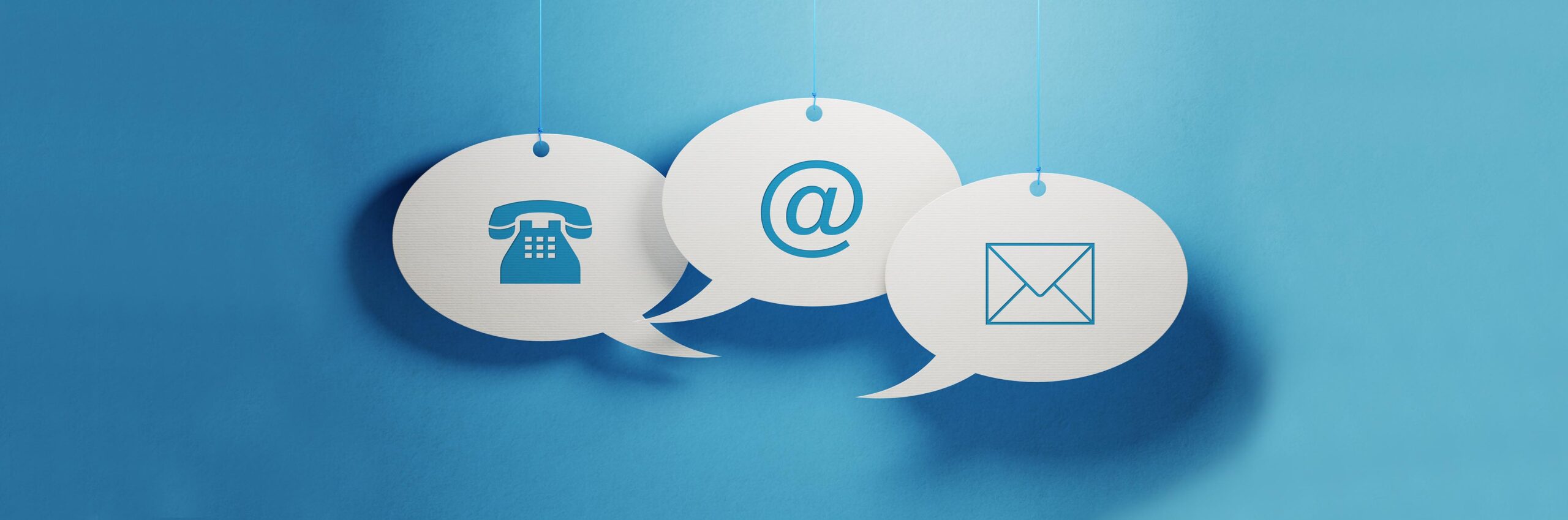 White chat bubbles hanging over a  blue background. Various contact us symbols are imprinted on chat bubbles. Horizontal composition with copy space.
